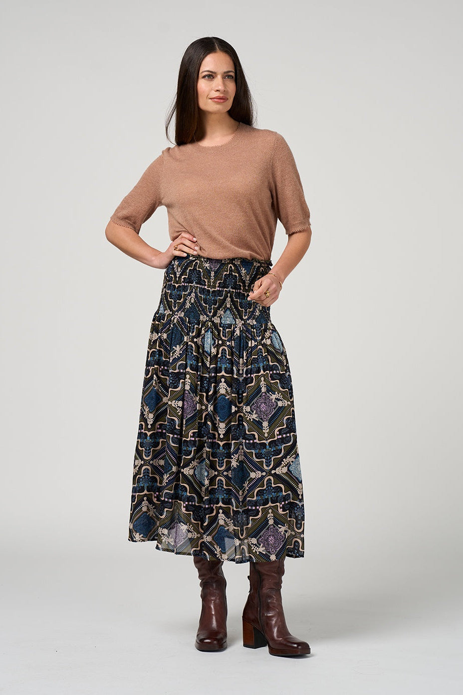 Woman wearing a patterned skirt and brown top on a white background