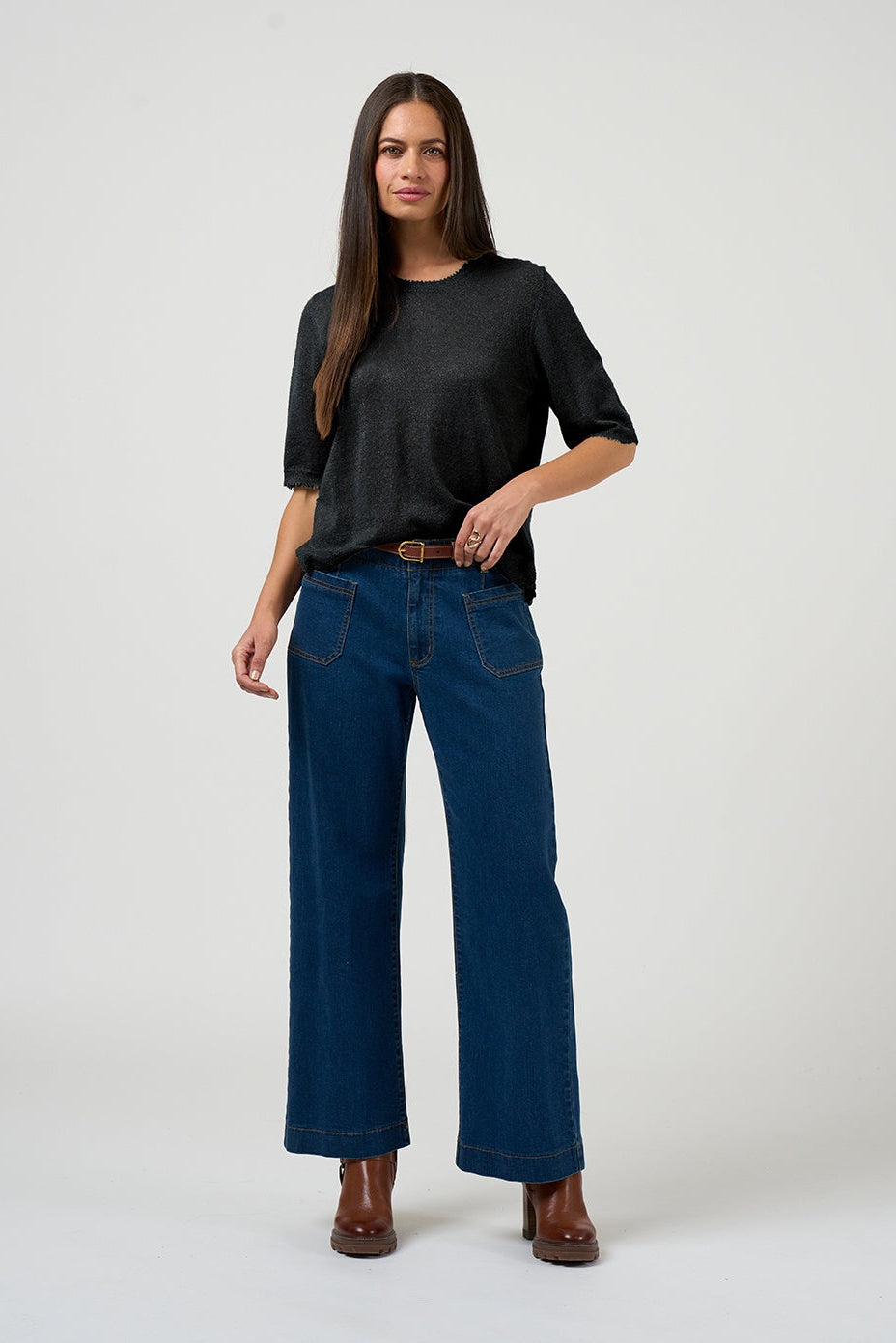 Woman wearing a black top and blue jeans on a white background