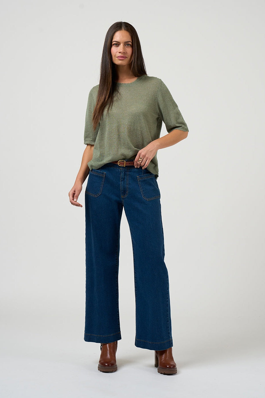 Woman wearing a green top and blue jeans on a white background