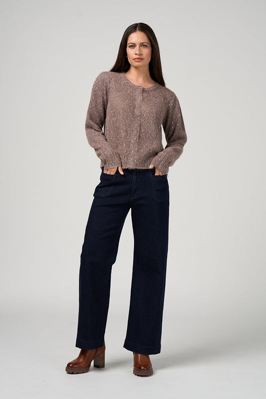 Woman wearing a brown sweater and dark pants on a white background