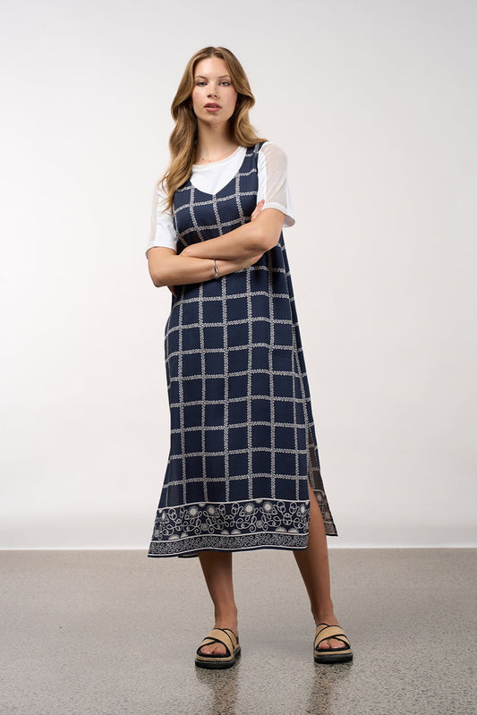 Woman wearing a blue checkered dress with a white top against a plain background