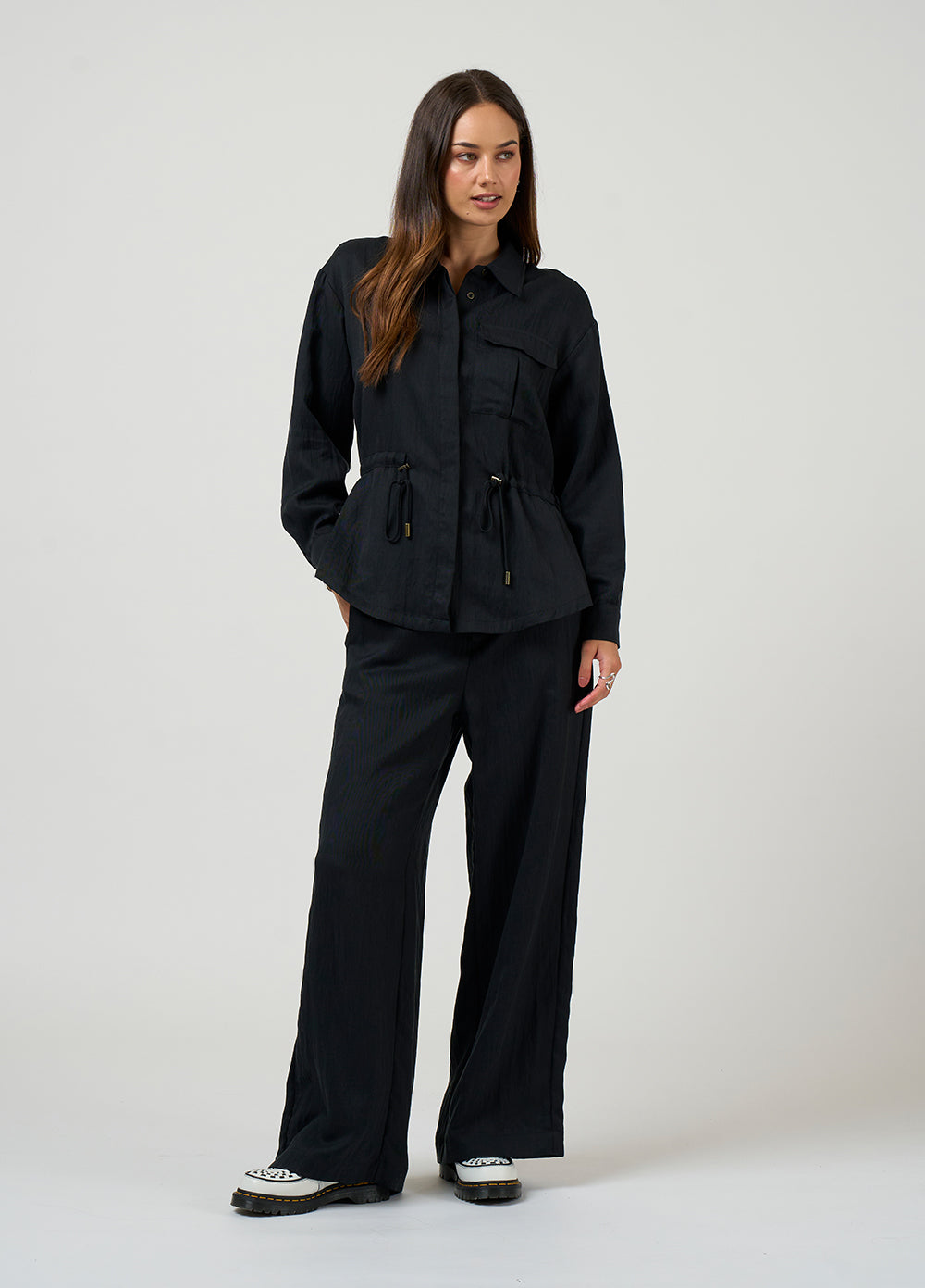 Woman wearing a black jacket and pants on a white background