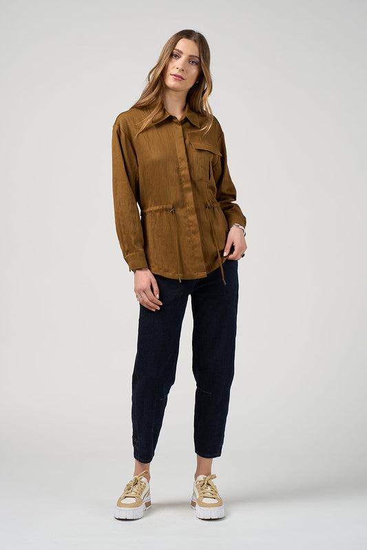 Woman wearing a brown jacket and navy pants on a white background