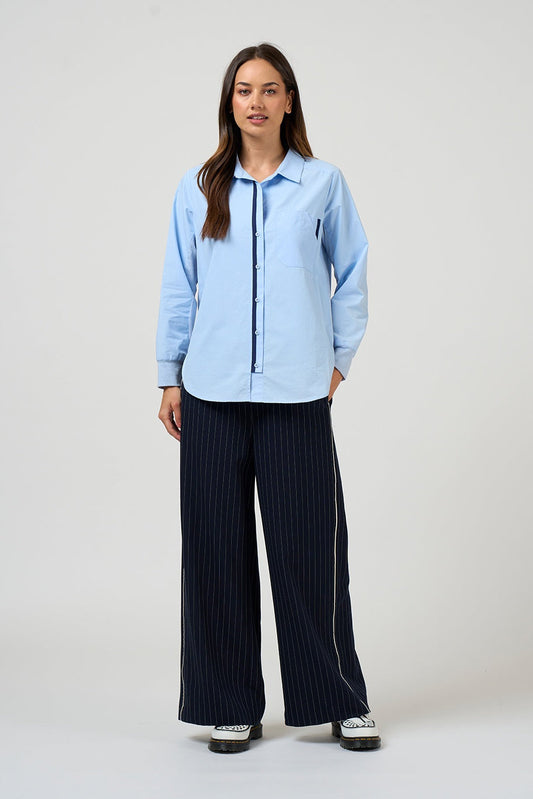 Woman wearing a light blue shirt and dark pinstripe pants on a white background