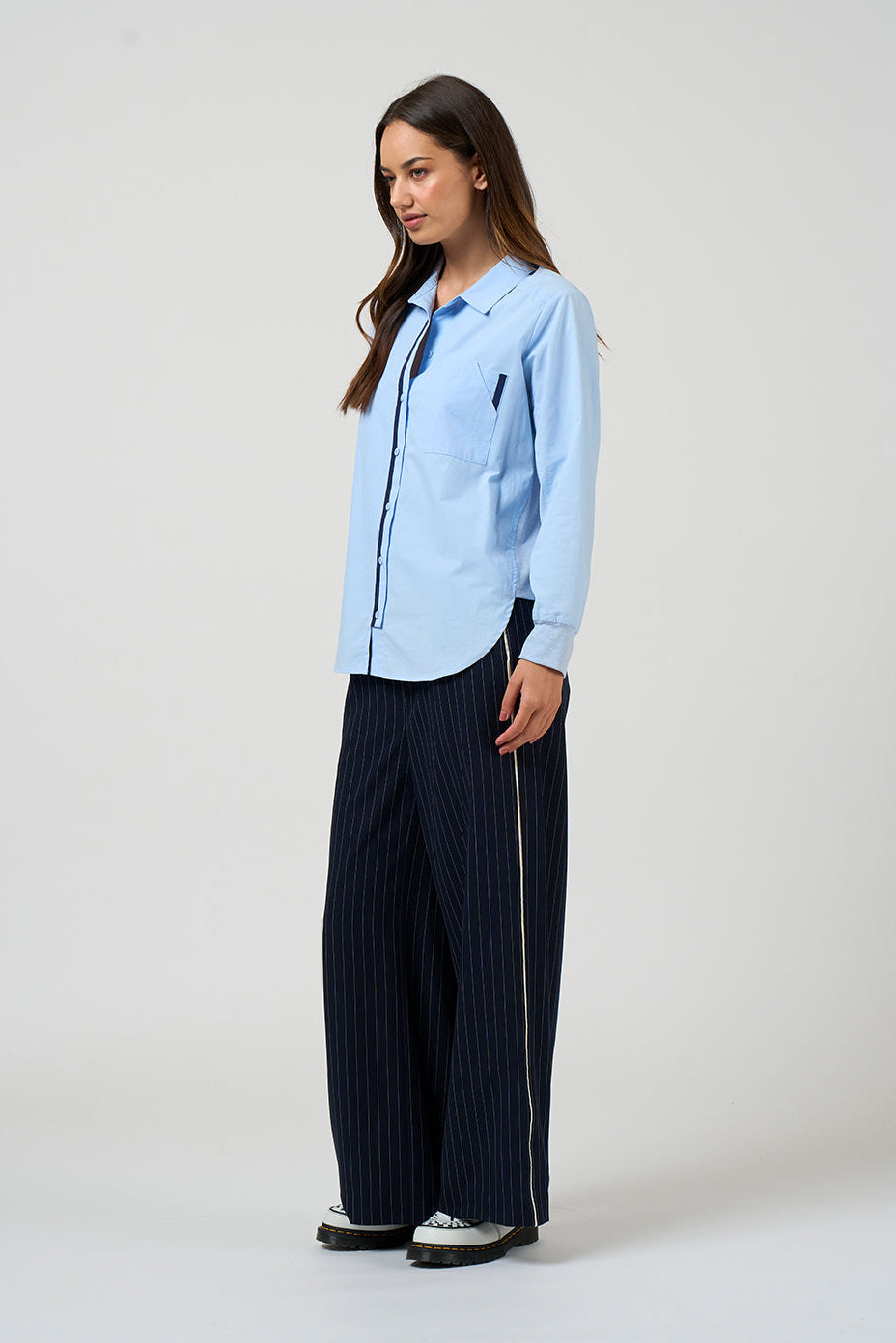 Woman wearing a light blue jacket and dark pinstripe pants on a white background