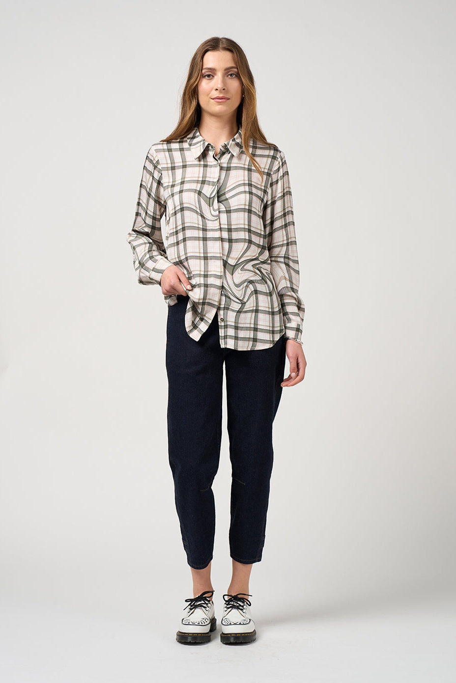 Woman wearing a plaid shirt and dark pants on a white background