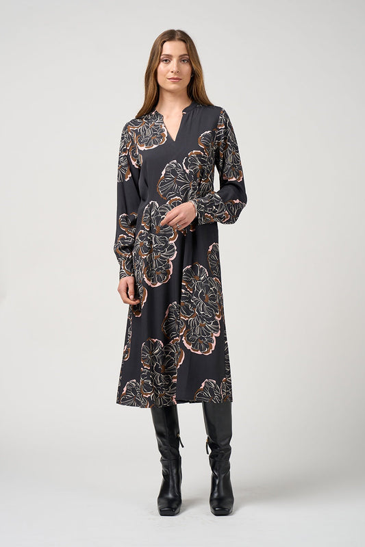 Woman wearing a black floral dress with black boots on a white background