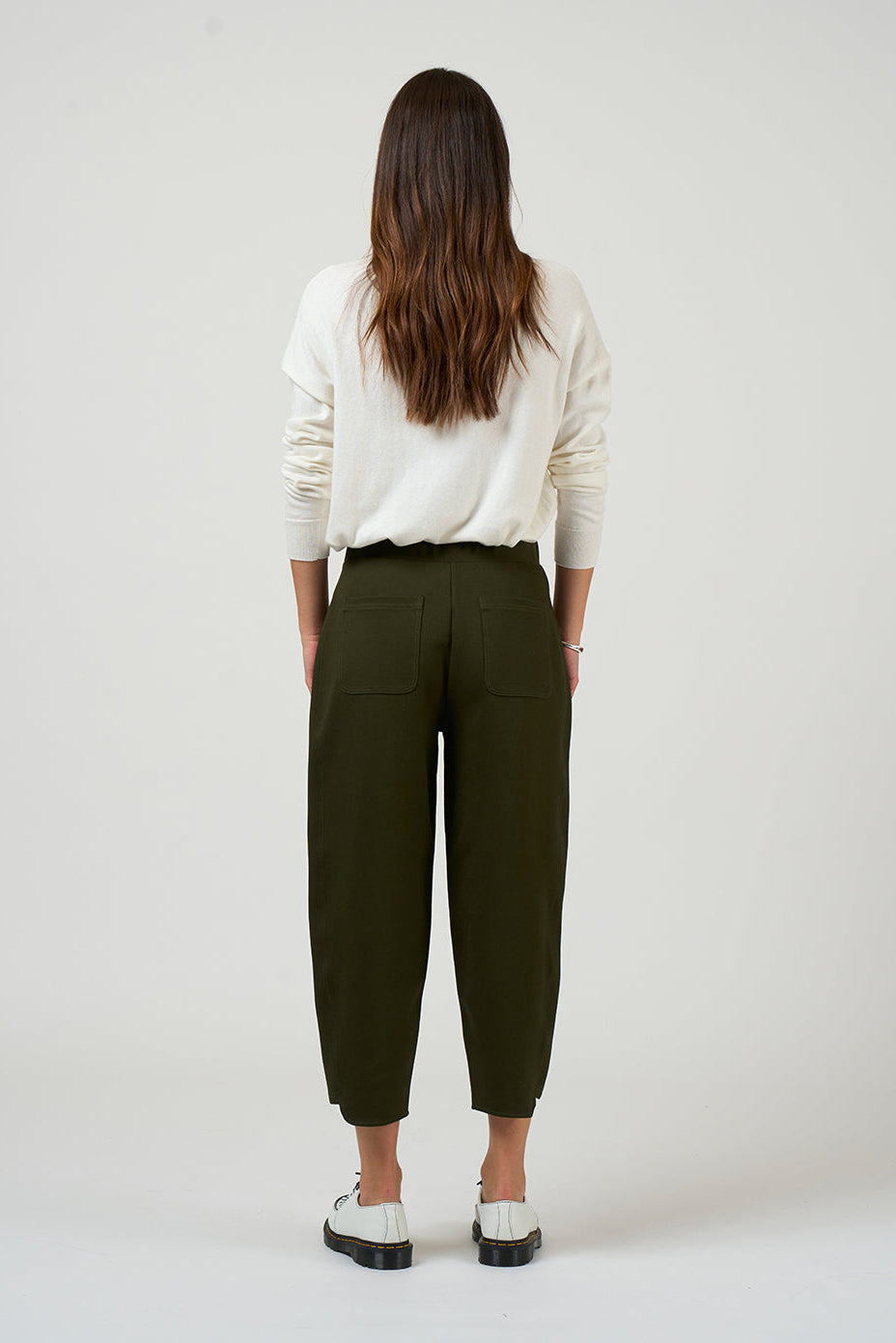 Person wearing a white shirt and green pants on a plain background