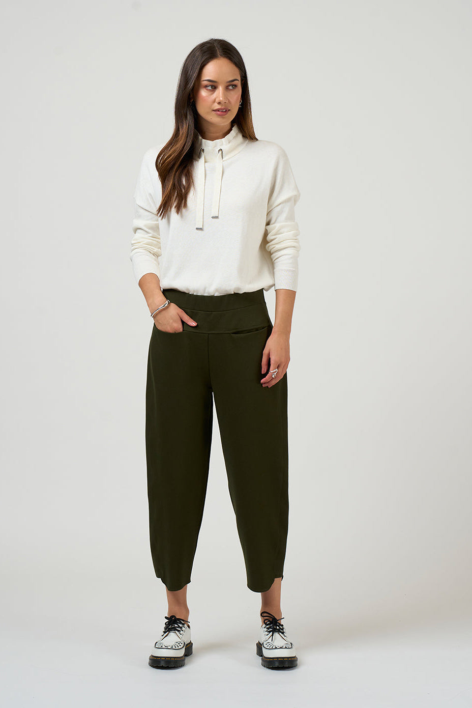Woman wearing a white blouse and green pants on a white background