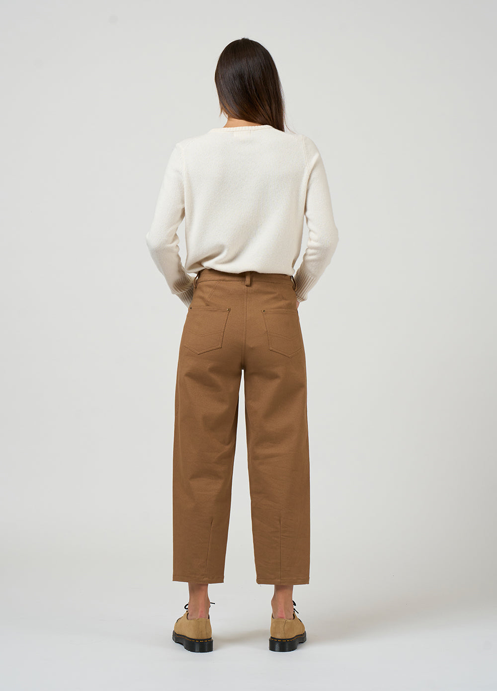 Person wearing a white sweater and brown pants on a white background