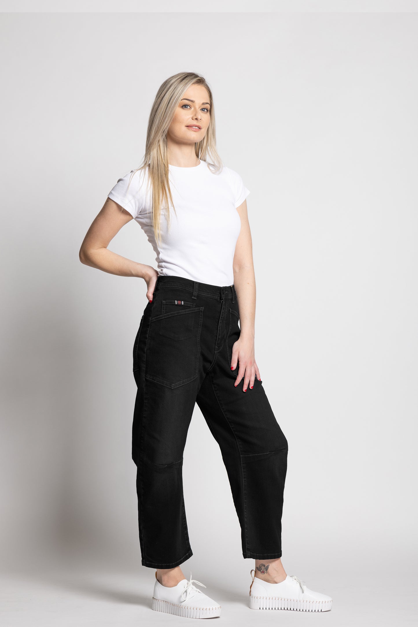 Woman wearing a white t-shirt and black pants on a plain background