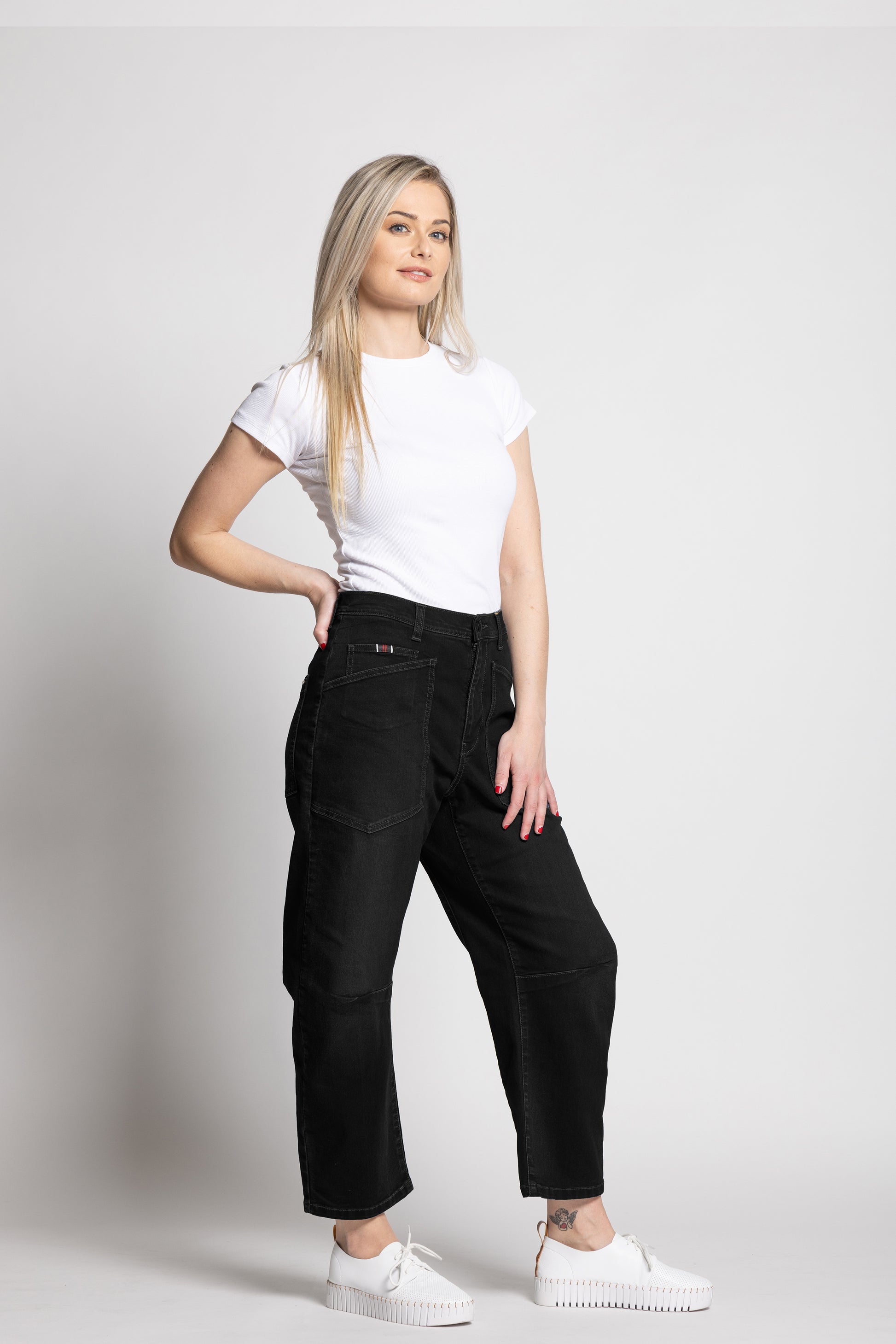 Woman wearing a white t-shirt and black pants on a plain background