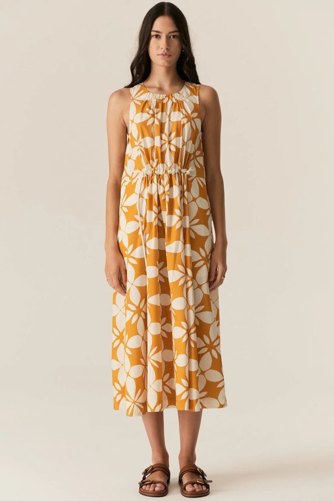 Woman wearing a yellow floral dress on a beige background