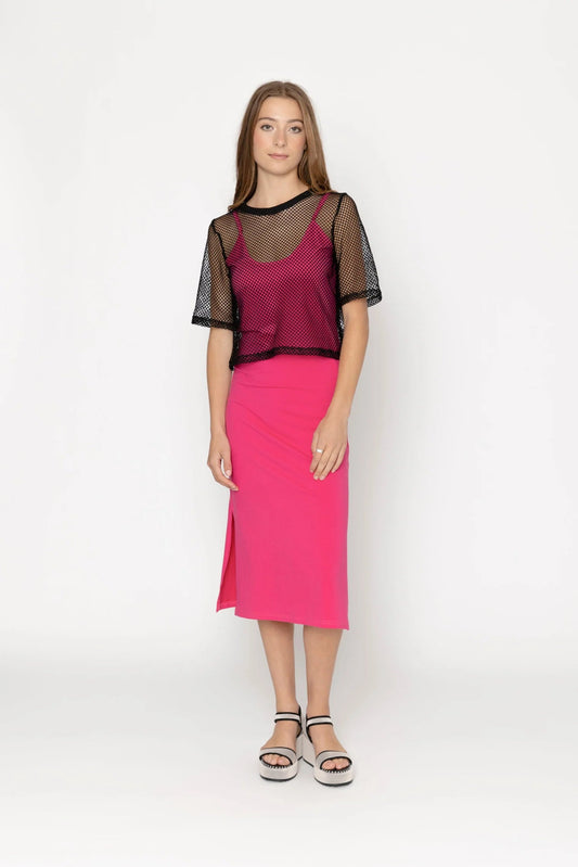 Woman wearing a pink skirt and black top with sheer sleeves on a white background