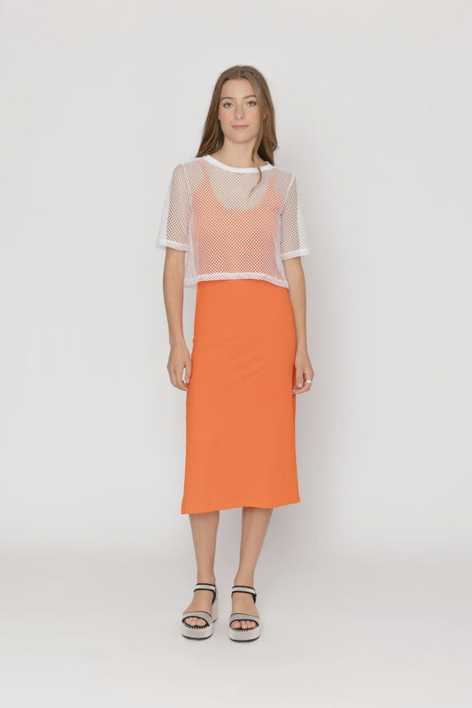 Woman wearing a white mesh top and orange skirt on a white background