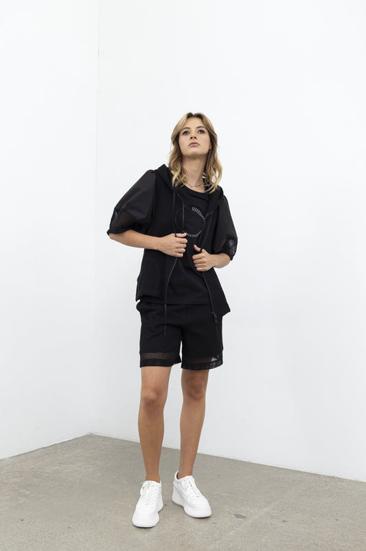 Person wearing a black outfit with white sneakers against a white background