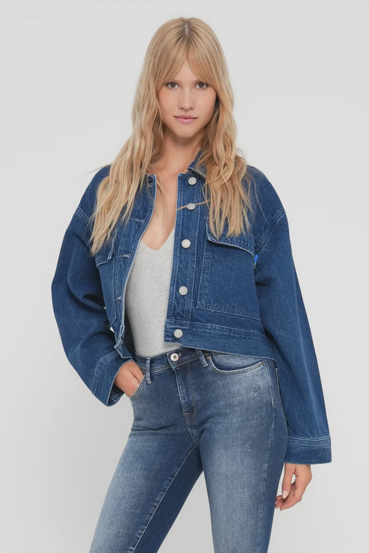 Woman wearing a blue denim jacket and jeans on a white background