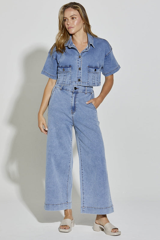 Woman wearing a denim outfit with a jacket and wide-leg jeans on a white background