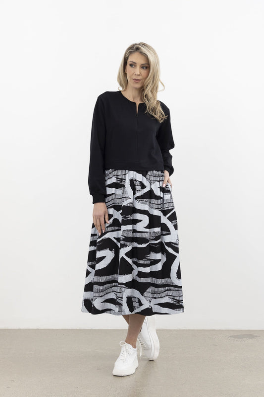 Woman wearing a black sweater and patterned skirt against a white background
