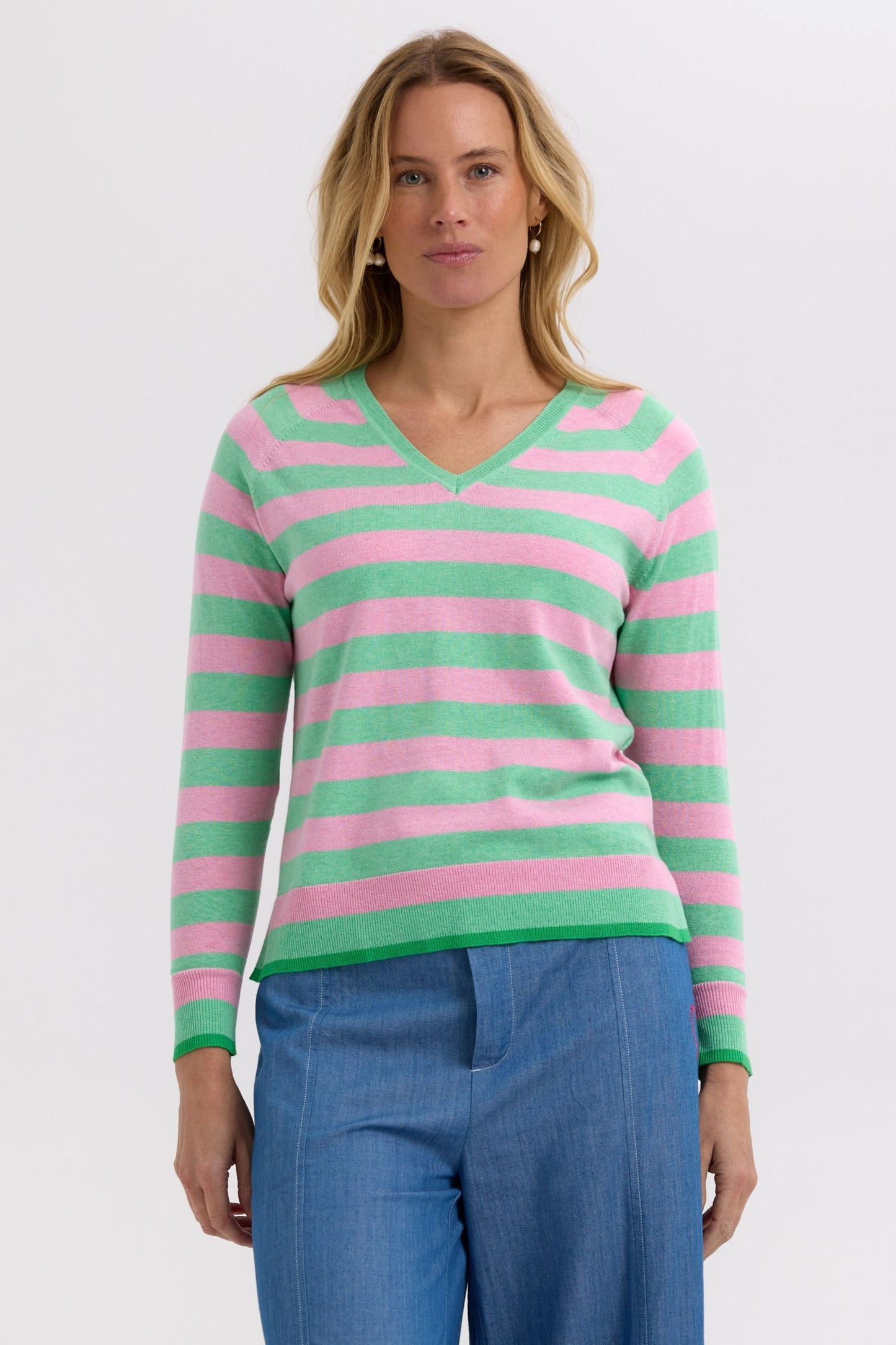 Woman wearing a pink and green striped sweater on a white background