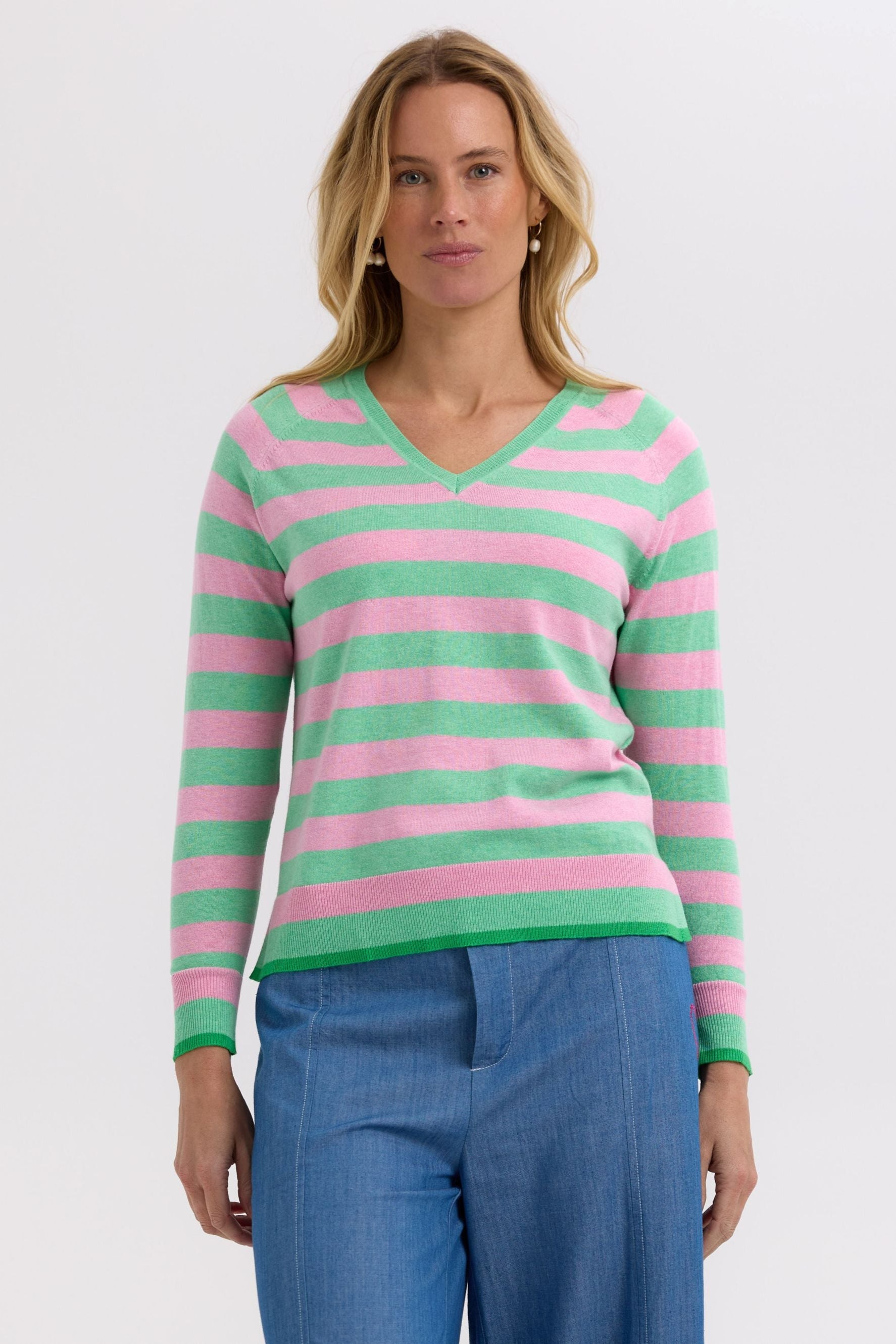 Woman wearing a pink and green striped sweater on a white background
