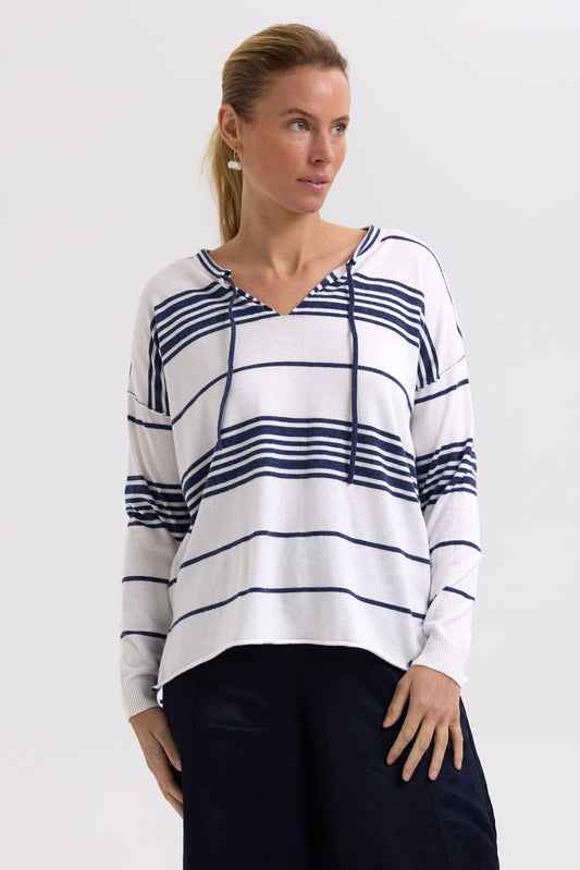 Woman wearing a white and blue striped sweater on a plain background
