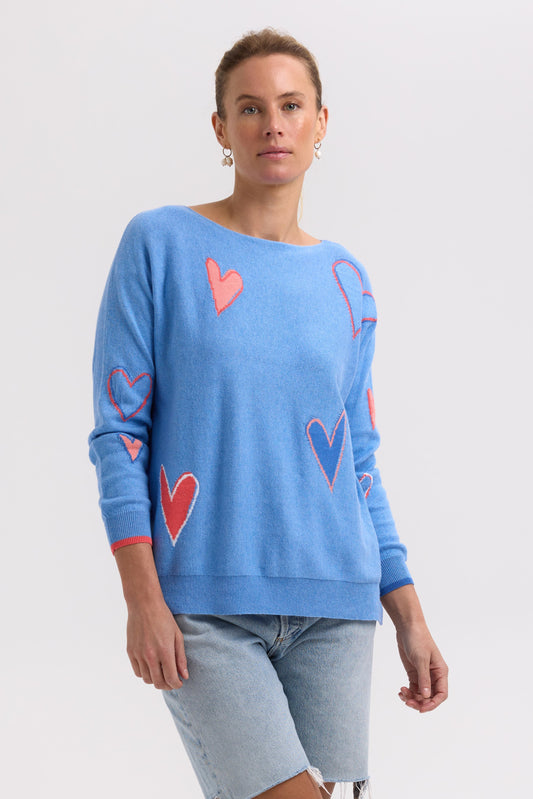 Woman wearing a blue sweater with red and pink heart patterns on a white background
