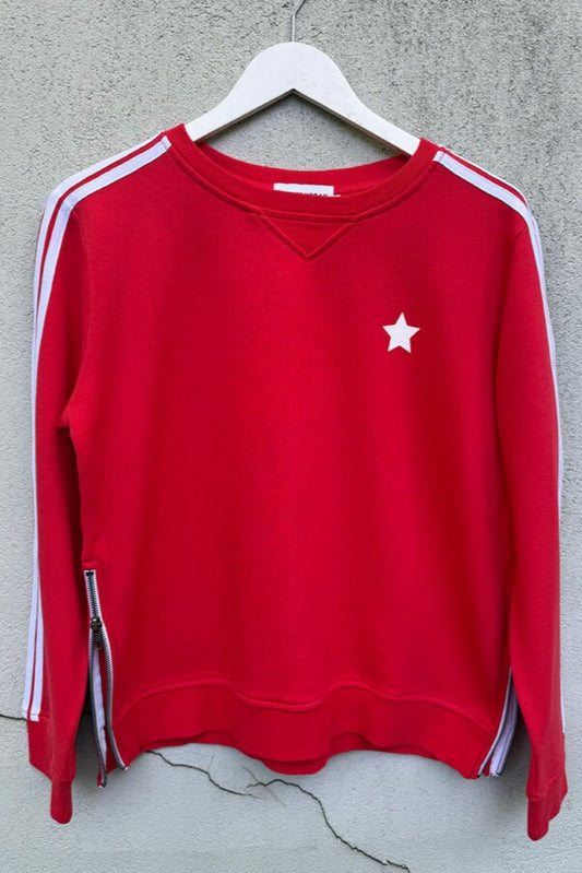 Red sweatshirt with white star and stripes on a hanger against a gray wall.