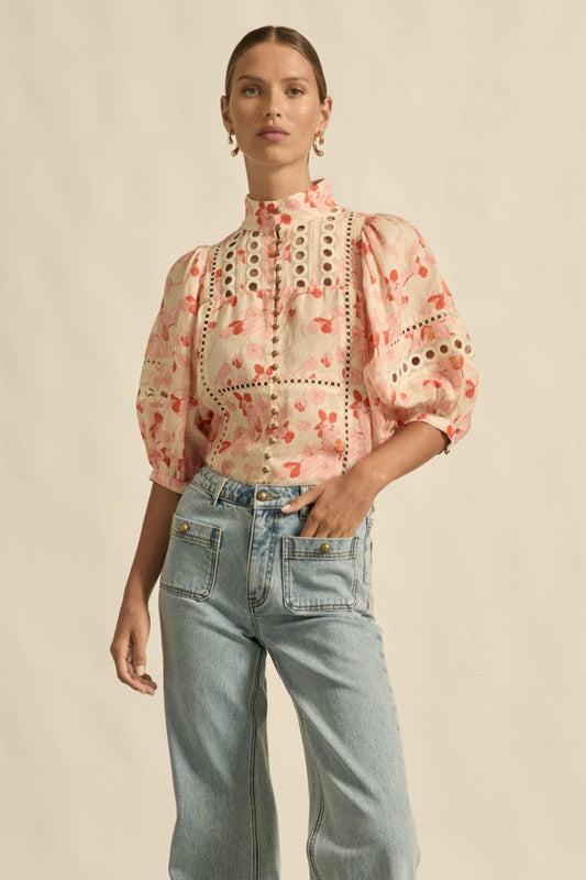 Woman wearing a floral blouse and jeans on a beige background