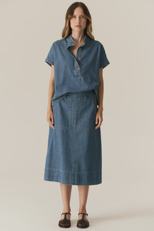 Woman wearing a blue denim outfit on a beige background
