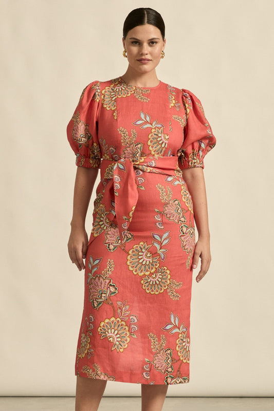 Woman wearing a red floral dress against a beige background